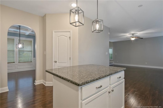 kitchen featuring a kitchen island, dark hardwood / wood-style flooring, dark stone countertops, decorative light fixtures, and white cabinetry