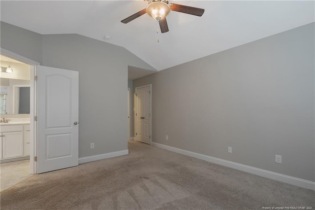 unfurnished bedroom featuring ceiling fan, lofted ceiling, ensuite bath, and light carpet