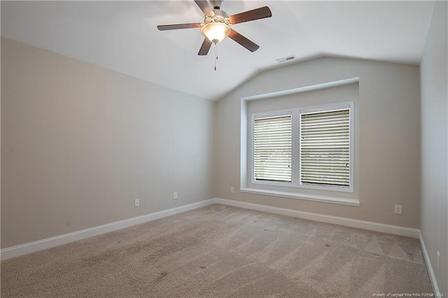 empty room with ceiling fan, vaulted ceiling, and light colored carpet