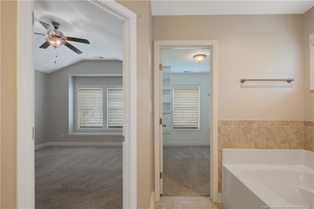 bathroom with lofted ceiling, a tub, and ceiling fan