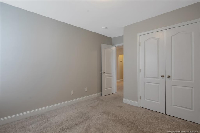 unfurnished bedroom featuring a closet and light colored carpet