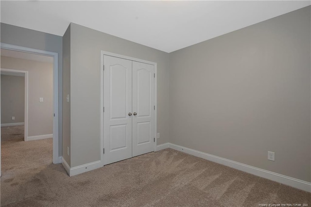 unfurnished bedroom featuring a closet and light colored carpet