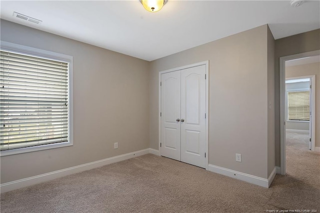 unfurnished bedroom featuring light carpet and a closet