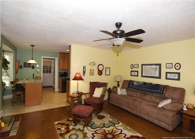 living room with dark hardwood / wood-style floors, a textured ceiling, and ceiling fan