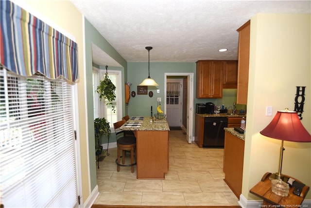 kitchen featuring pendant lighting, a breakfast bar, sink, light stone counters, and dishwasher