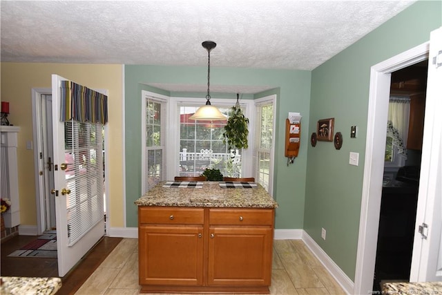 3760 Berkley Ln, Lumberton, NC 28358 - kitchen featuring light tile patterned floors, a textured ceiling, hanging light fixtures, light stone counters, and brown cabinetry