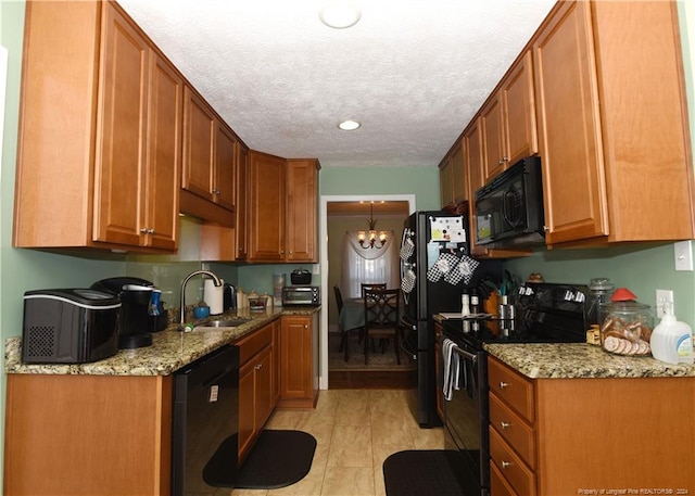 kitchen with black appliances, sink, a chandelier, and light stone countertops