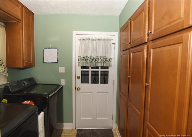 washroom with a textured ceiling, washer and dryer, tile patterned floors, and cabinets