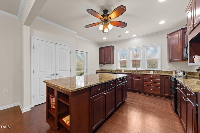 kitchen featuring dark hardwood / wood-style flooring, a kitchen island, light stone counters, and range with two ovens