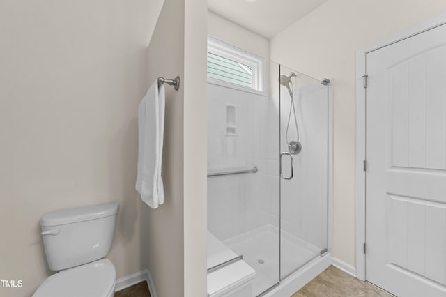 bathroom featuring a shower with door and toilet