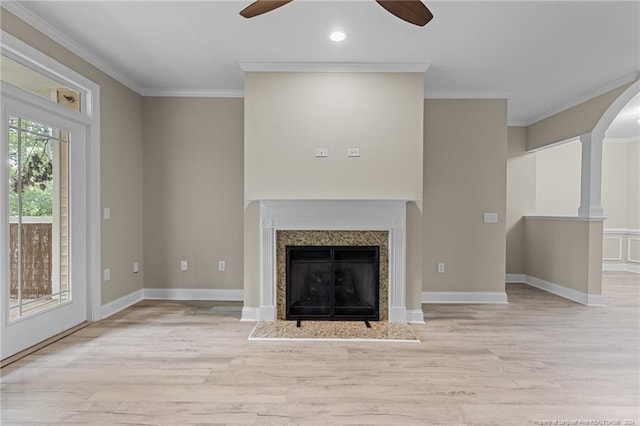 unfurnished living room featuring crown molding, ceiling fan, a high end fireplace, and light hardwood / wood-style flooring