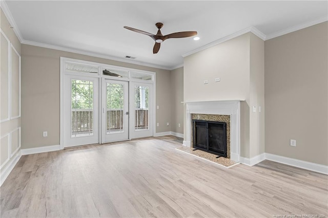 unfurnished living room featuring a high end fireplace, light hardwood / wood-style flooring, ornamental molding, and ceiling fan