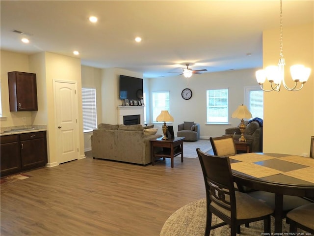 dining space with ceiling fan with notable chandelier and wood-type flooring