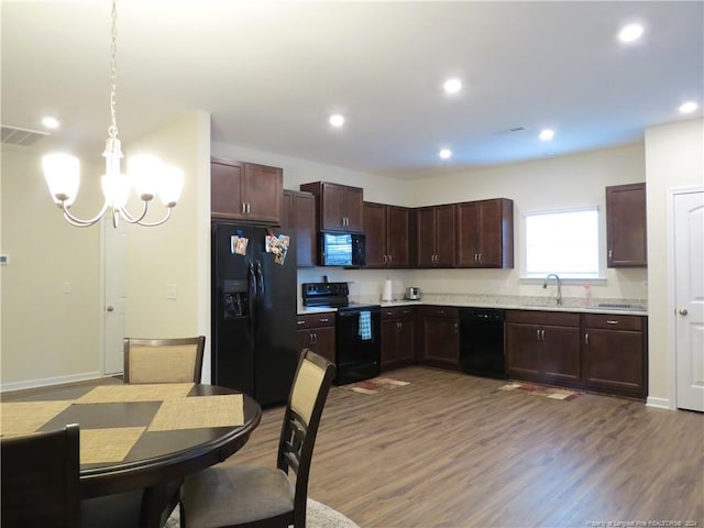 kitchen featuring black appliances, wood-type flooring, sink, a chandelier, and decorative light fixtures