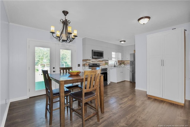 dining space featuring crown molding, dark hardwood / wood-style flooring, a notable chandelier, sink, and french doors