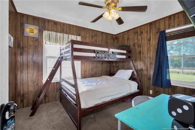 carpeted bedroom featuring ornamental molding, ceiling fan, and wood walls