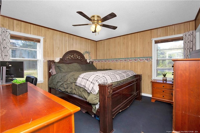 carpeted bedroom featuring wood walls, a textured ceiling, multiple windows, and ceiling fan