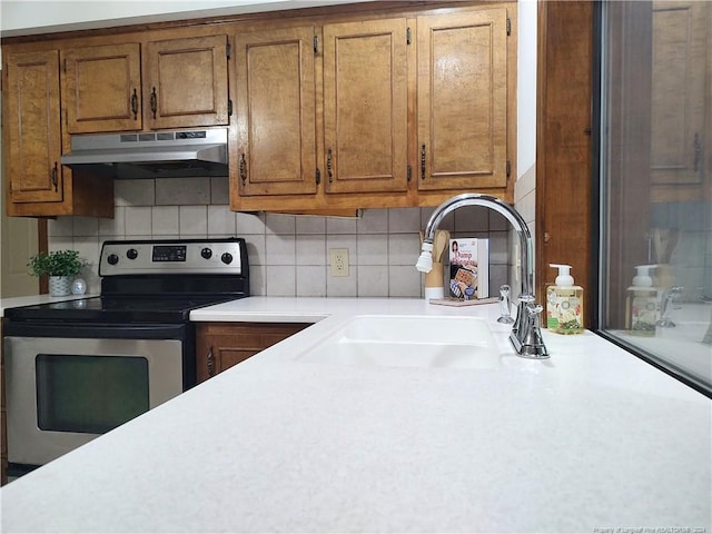 kitchen featuring decorative backsplash, stainless steel electric range oven, and sink