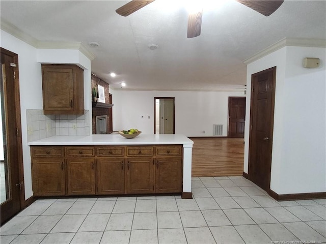 kitchen featuring ceiling fan, kitchen peninsula, backsplash, light wood-type flooring, and crown molding