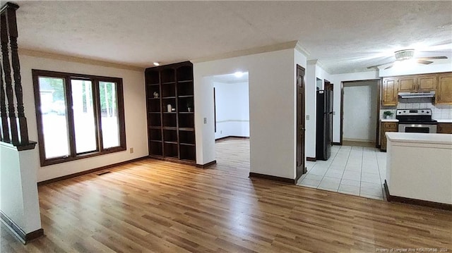 interior space with wood-type flooring, ceiling fan, ornamental molding, and a textured ceiling