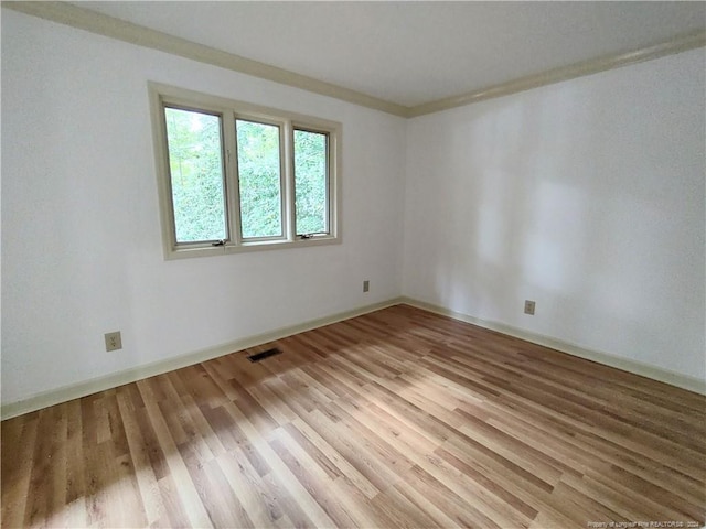 empty room featuring wood-type flooring and crown molding