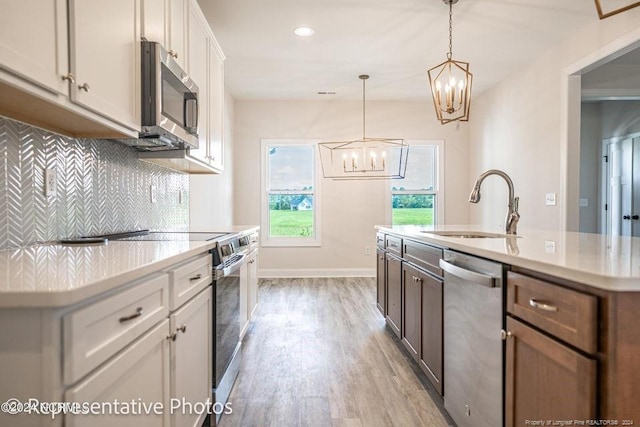 kitchen with a kitchen island with sink, stainless steel appliances, light hardwood / wood-style floors, and white cabinetry