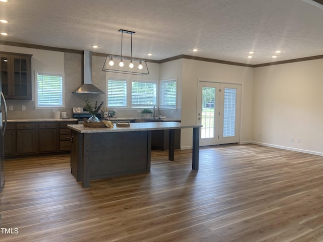 6733 Oscar Barham Rd, Wake Forest, NC 27587 - kitchen with wall chimney exhaust hood, a center island, a textured ceiling, ornamental molding, and wood finished floors