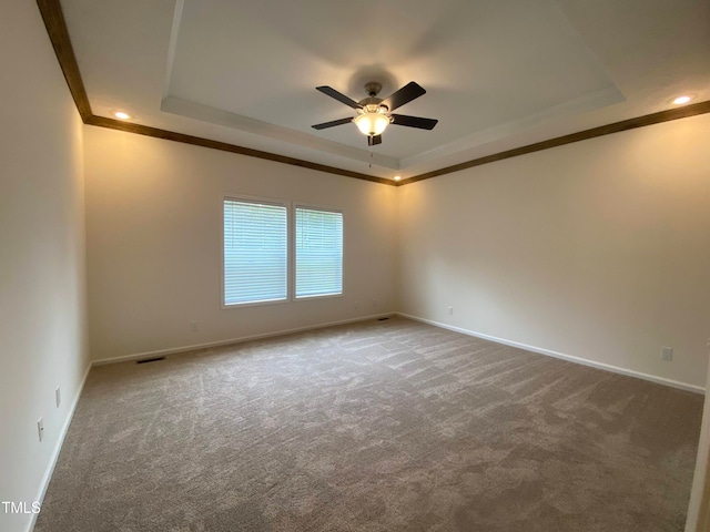 carpeted spare room with ceiling fan, crown molding, and a tray ceiling