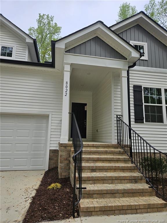 entrance to property featuring board and batten siding, an attached garage, and driveway