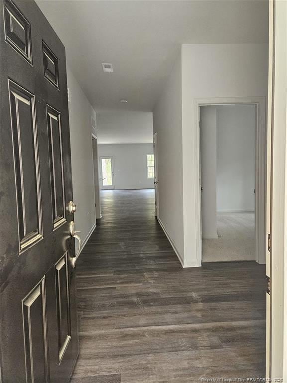 hall featuring baseboards and dark wood-style flooring