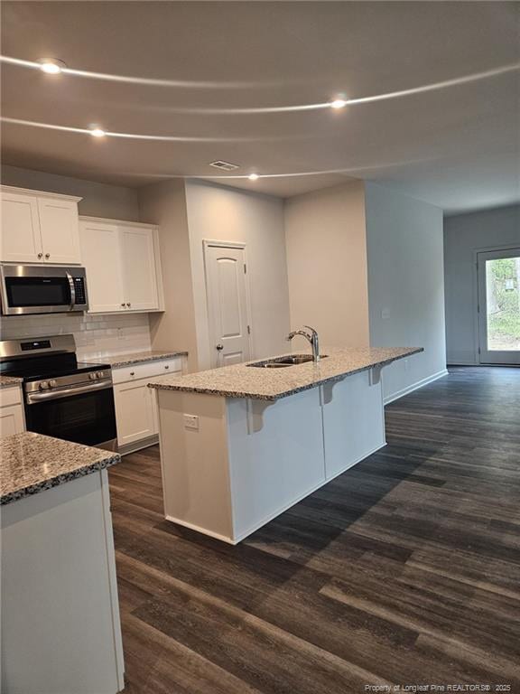 kitchen featuring white cabinets, a sink, light stone counters, dark wood-type flooring, and appliances with stainless steel finishes