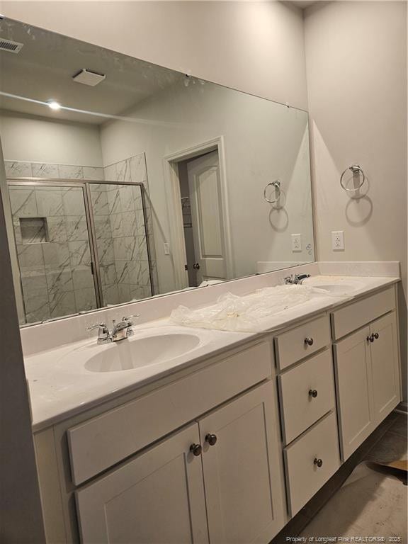 bathroom featuring double vanity, visible vents, a stall shower, and a sink