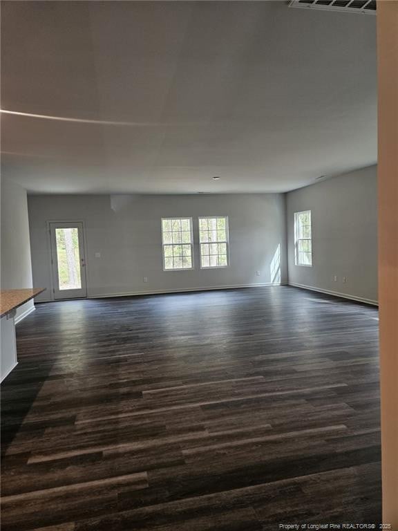 unfurnished room with visible vents, baseboards, and dark wood-style flooring