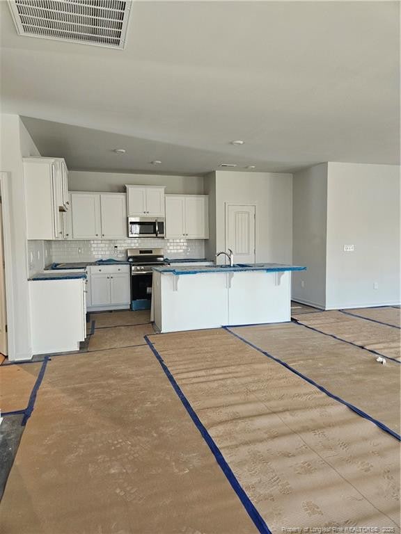 kitchen featuring white cabinets, an island with sink, stainless steel appliances, visible vents, and decorative backsplash