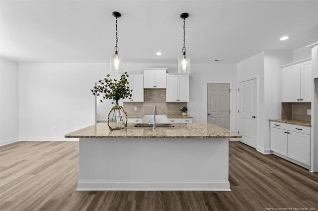 kitchen with light stone counters, dark wood-type flooring, and a sink