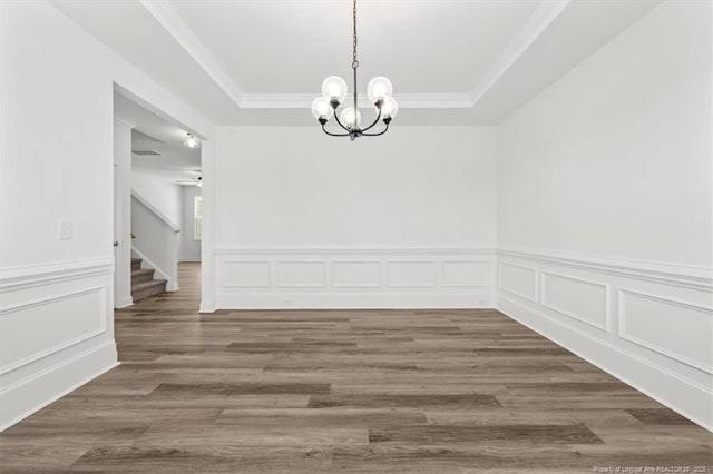 unfurnished dining area with wood finished floors, stairway, a raised ceiling, and an inviting chandelier