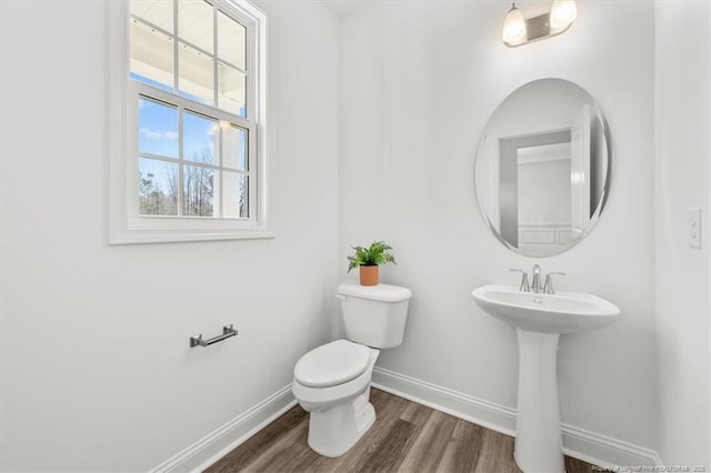 half bathroom featuring toilet, a sink, baseboards, and wood finished floors