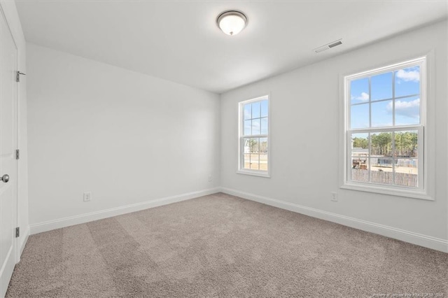 carpeted spare room featuring visible vents and baseboards