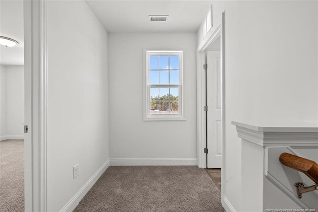 hall with carpet floors, visible vents, and baseboards