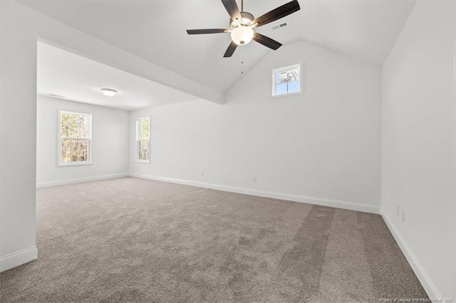 carpeted spare room with visible vents, lofted ceiling, a wealth of natural light, and baseboards