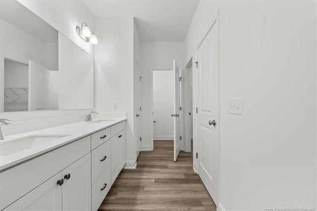 bathroom with double vanity, a sink, baseboards, and wood finished floors