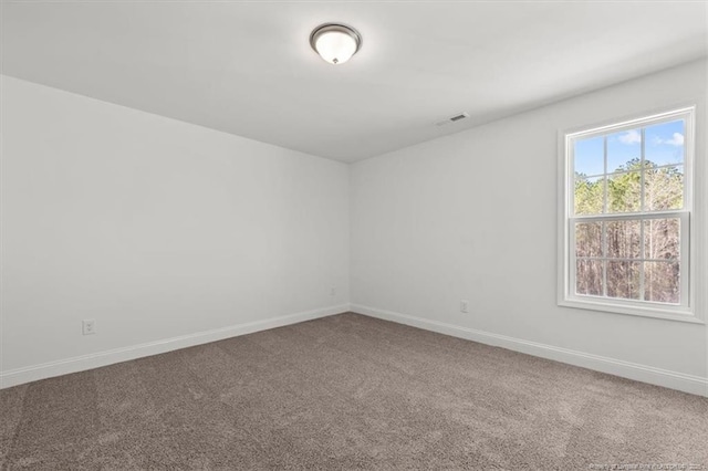 empty room with carpet floors, visible vents, and baseboards