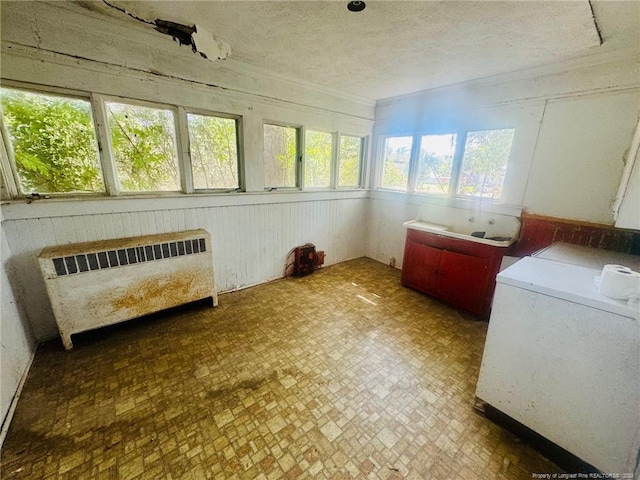 sunroom / solarium with washer / dryer, a healthy amount of sunlight, and radiator heating unit