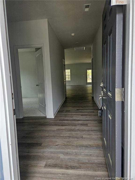 corridor featuring dark wood-type flooring, visible vents, and baseboards