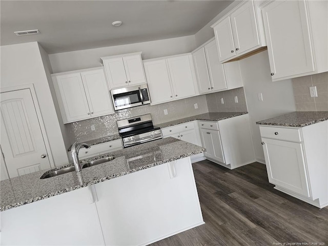 kitchen featuring dark stone counters, white cabinetry, stainless steel appliances, and a sink