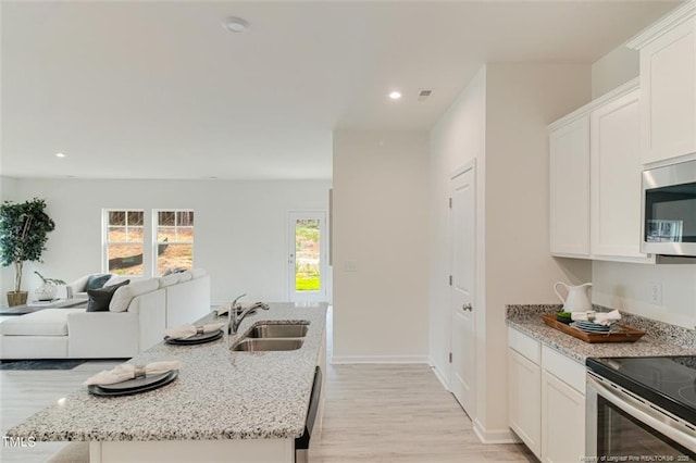 kitchen with white cabinets, light wood-type flooring, appliances with stainless steel finishes, and a sink