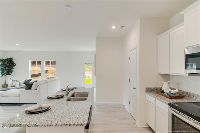 kitchen with white cabinets, stainless steel appliances, sink, and a kitchen island with sink