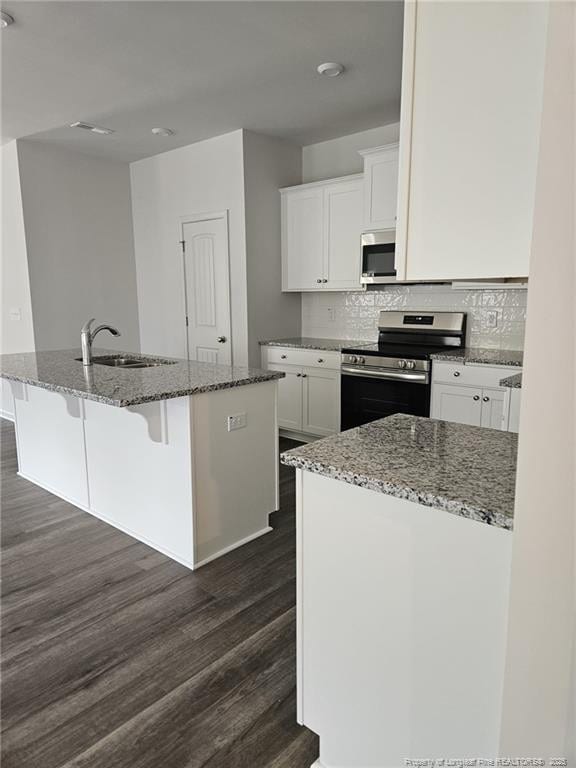 kitchen with a sink, stone counters, appliances with stainless steel finishes, and white cabinetry