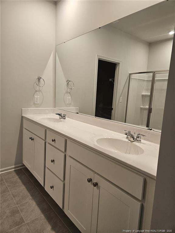full bath with double vanity, tile patterned floors, a stall shower, and a sink