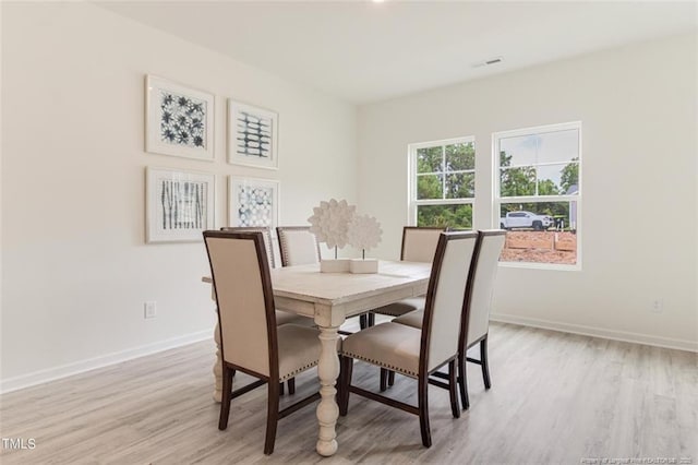 dining space with light wood-style floors, baseboards, and visible vents